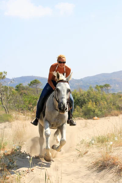 Bella donna bionda in bikini cavalcando un cavallo bianco — Foto Stock