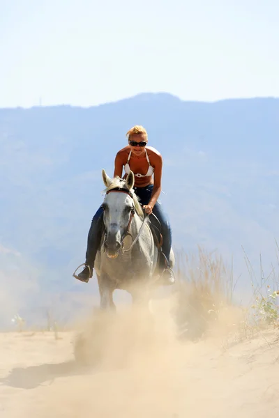 美丽的金发女人骑着一匹白马的比基尼 — 图库照片