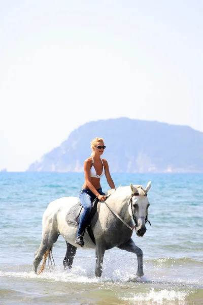 Mulher loira bonita em biquíni montando um cavalo branco — Fotografia de Stock