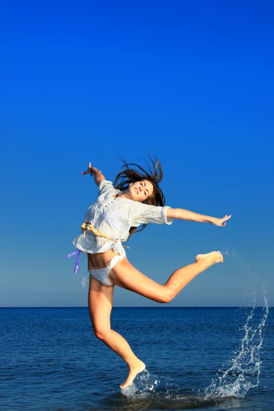 Gyönyörű lány jumping kecsesen a strandon — Stock Fotó