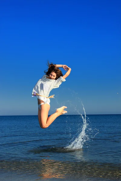 Schönes Mädchen, das anmutig am Strand springt — Stockfoto