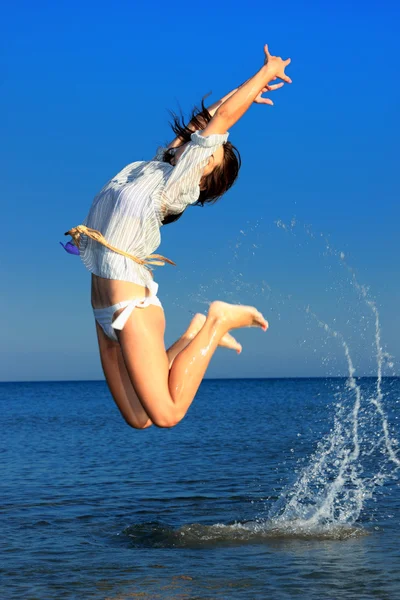 Vacker flicka hoppande graciöst på stranden — Stockfoto