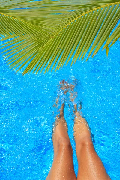 Vrouwen benen spetteren in tropisch zwembad — Stockfoto