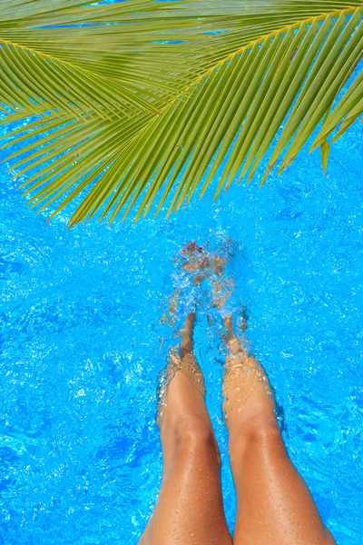 Women legs splashing in tropical swimming pool — Stock Photo, Image