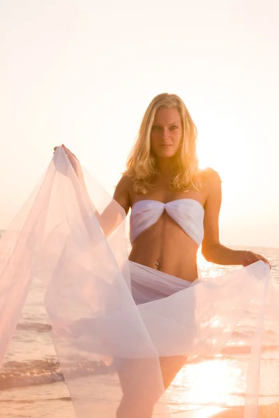 Woman wrapped in wedding veil on the beach Stock Picture