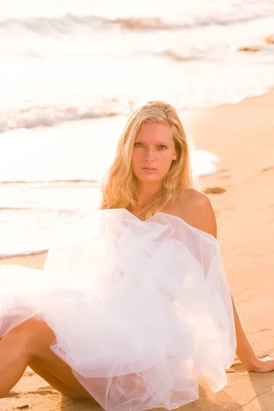 Woman wrapped in wedding veil on the beach Stock Image