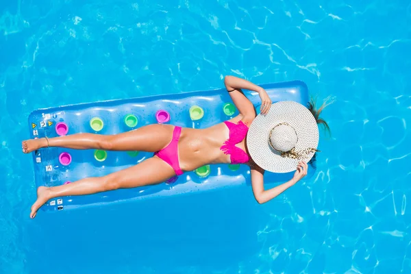 Young woman on a lilo in the swimming pool — Stock Photo, Image