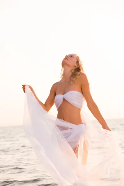 Mooi meisje met witte stof op het strand. — Stockfoto