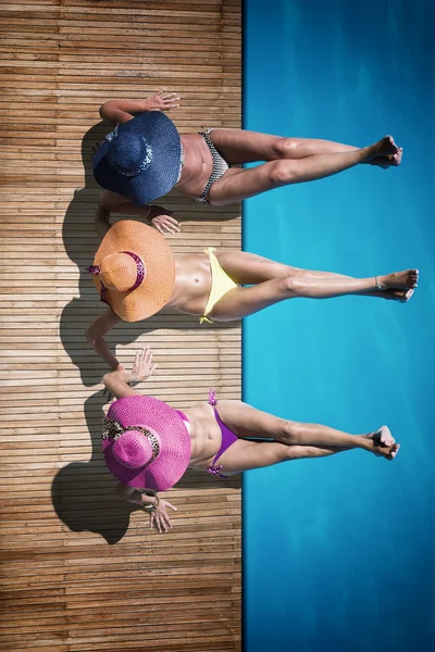 Women reaxing on the deck by the swimming pool — Stock Photo, Image