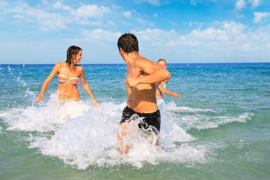 neşeli bir grup insan denizde eğleniyor