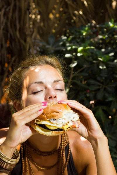 Femme mangeant un cheeseburger — Photo