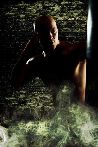 Boxeador hombre durante el boxeo golpeando bolsa pesada en el entrenamiento de fitness — Foto de Stock