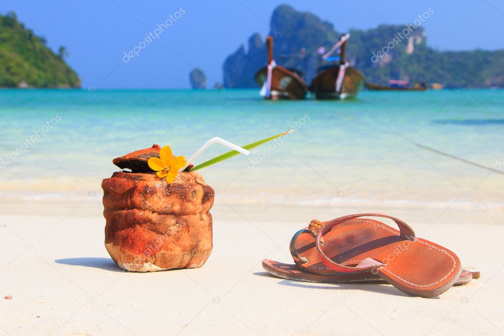 Coconut cocktail with drinking straw and sandals