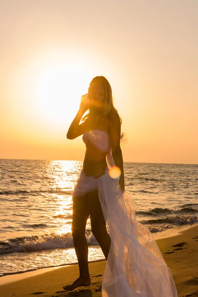 Vrouw gewikkeld in huwelijkssluier op het strand — Stockfoto