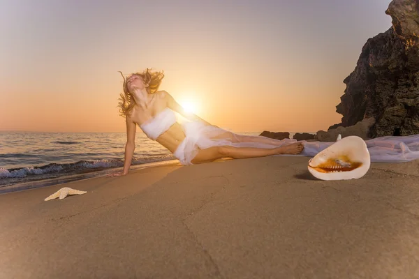 Frau in Hochzeitsschleier gehüllt am Strand — Stockfoto