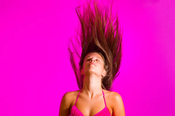 Брюнетка в бикини позирует на розовом фоне — стоковое фото