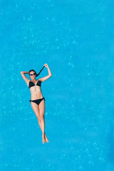 Mujer flotando sobre el agua de la piscina —  Fotos de Stock