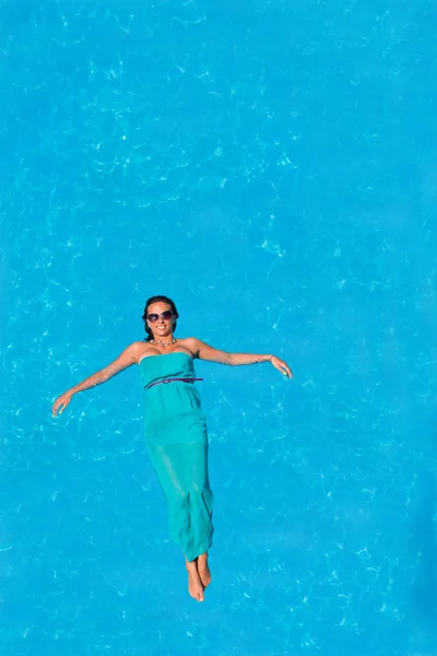 Femme flottant au-dessus de l'eau de piscine — Photo