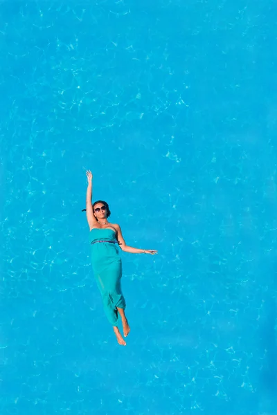 Mulher flutuando acima da água da piscina — Fotografia de Stock