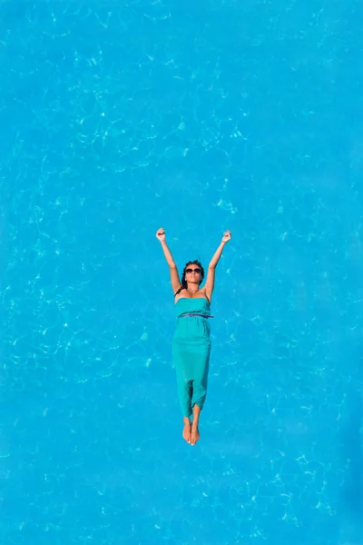 Femme flottant au-dessus de l'eau de piscine — Photo