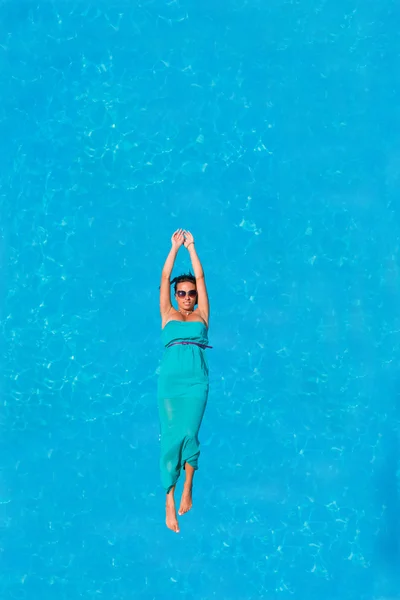 Woman floating above pool water — Stock Photo, Image
