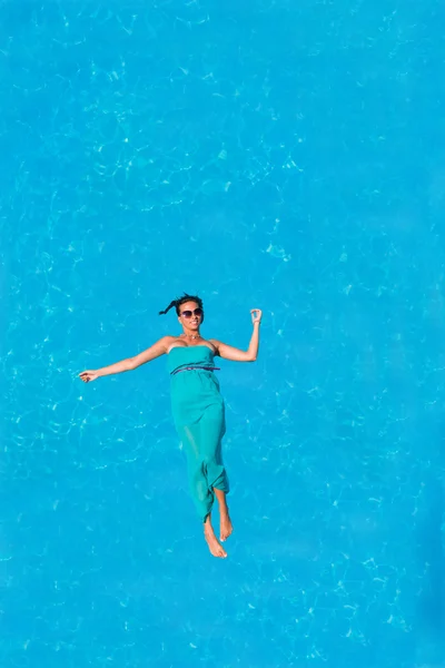 Femme flottant au-dessus de l'eau de piscine — Photo