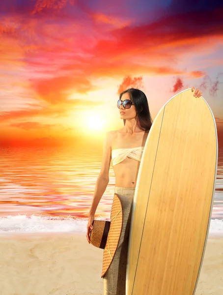 Frau mit Surfbrett am Strand bei Sonnenuntergang — Stockfoto
