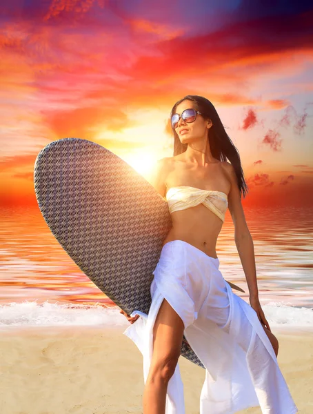 Mujer con tabla de surf en la playa al atardecer —  Fotos de Stock