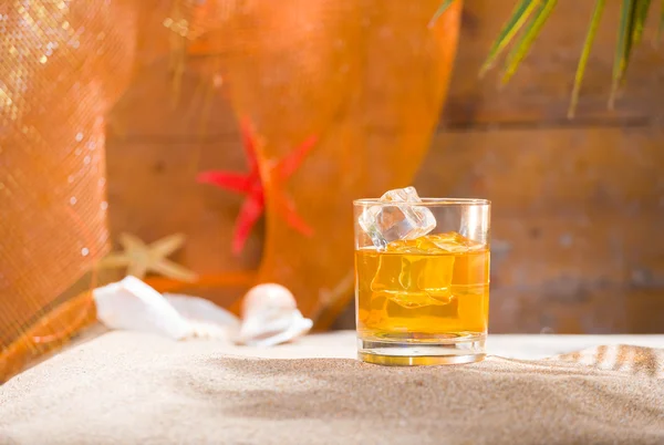 Whisky liqueur glass with ice cubes on the beach — Stock Photo, Image