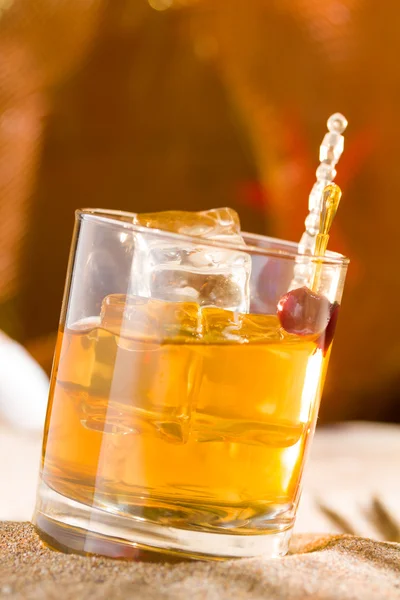 Whisky liqueur glass with ice cubes on the beach — Stock Photo, Image