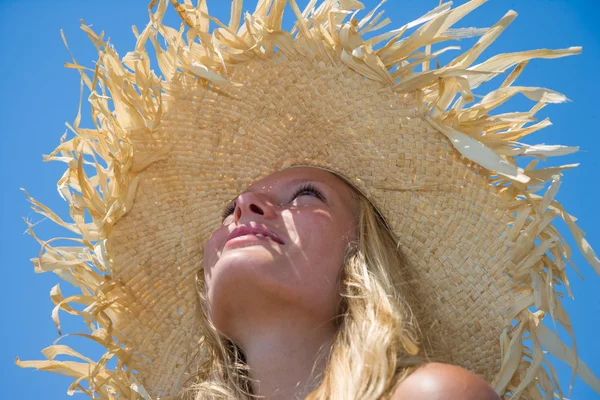 Loira usando chapéu de palha em uma bela praia ensolarada — Fotografia de Stock