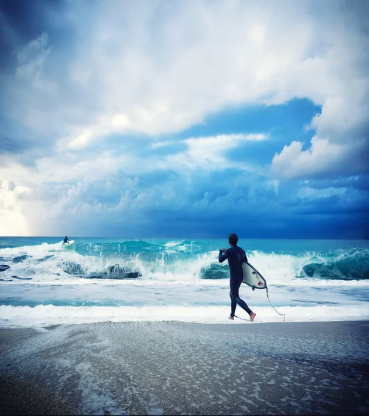 Joven surfista masculino de pie mirando al océano . — Foto de Stock
