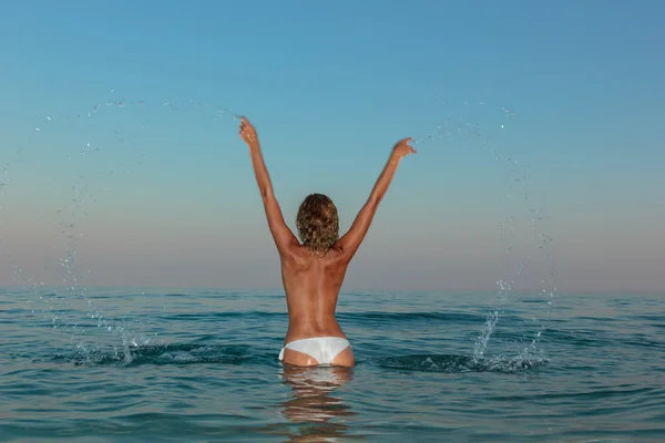 Sexy joven con el pelo largo posando en la playa al atardecer — Foto de Stock