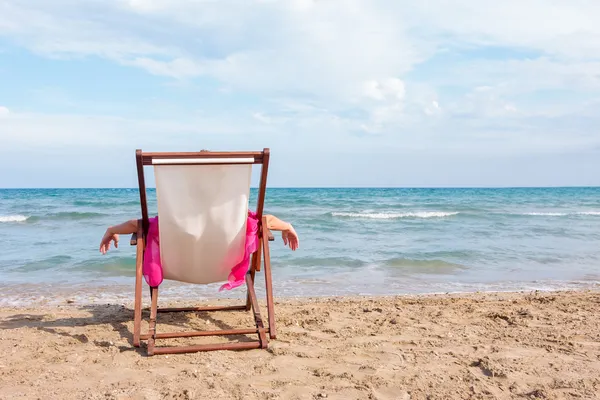 Lány ül egy széken, a strandon — Stock Fotó