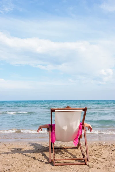 Lány ül egy széken, a strandon — Stock Fotó