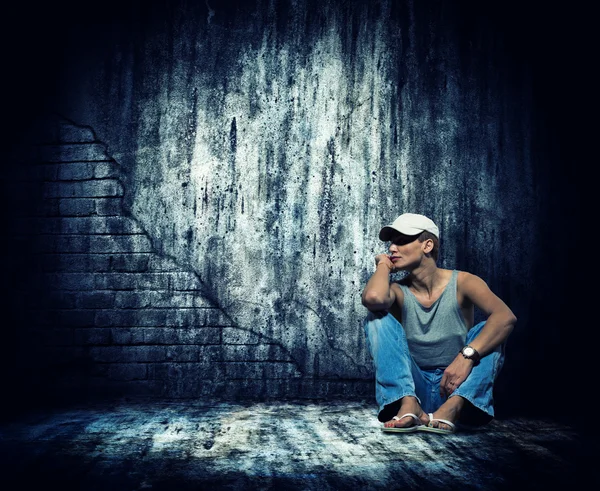 Женщина сидит у бетонной стены — стоковое фото