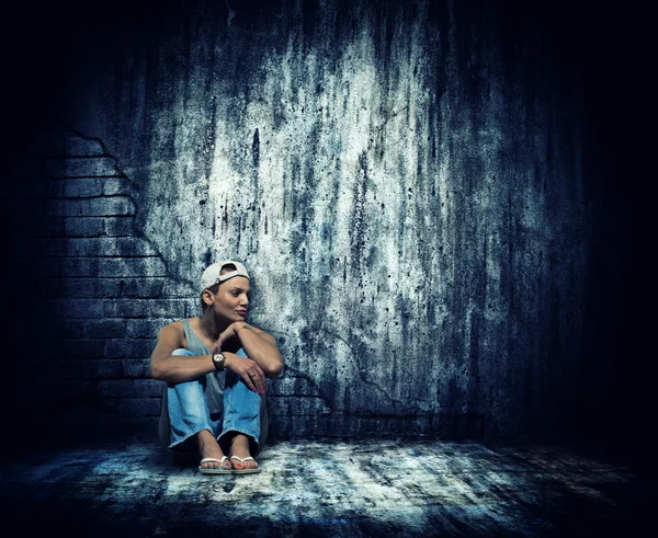 Woman sitting by the concrete wall — Stock Photo, Image