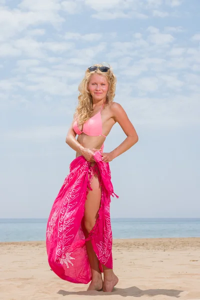 Młoda kobieta w czerwonym bikini gospodarstwa chusta na plaży — Zdjęcie stockowe