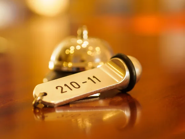 Колокол в отеле и ключ лежат на столе — стоковое фото