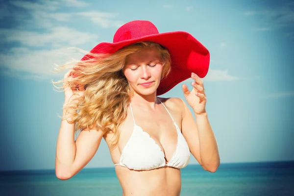 Mujer joven en bikini blanco sosteniendo sarong en la playa — Foto de Stock