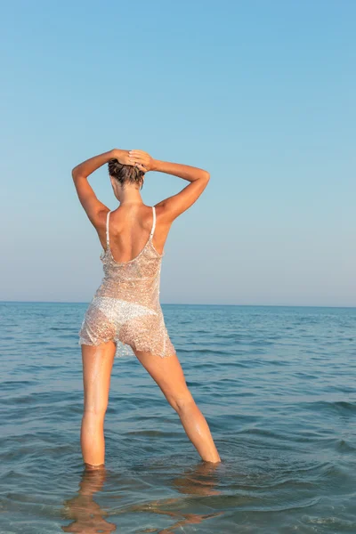 Jong sexy meisje in een bikini en natte shirt op het strand — Stockfoto