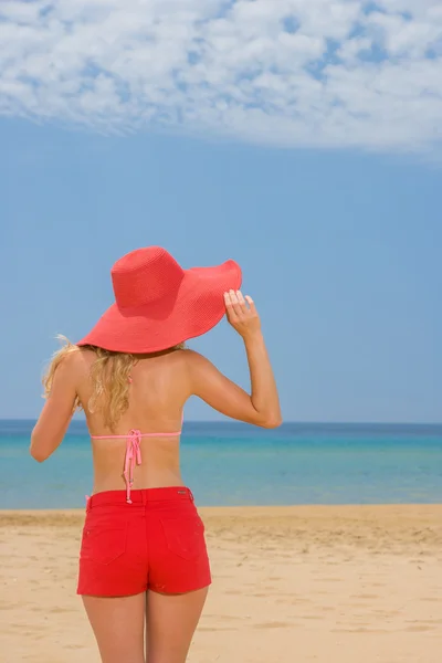 Vrouw op tropisch strand in rode korte broek — Stockfoto