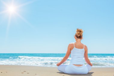 beyaz kadını kumsalda Yoga uygulamak