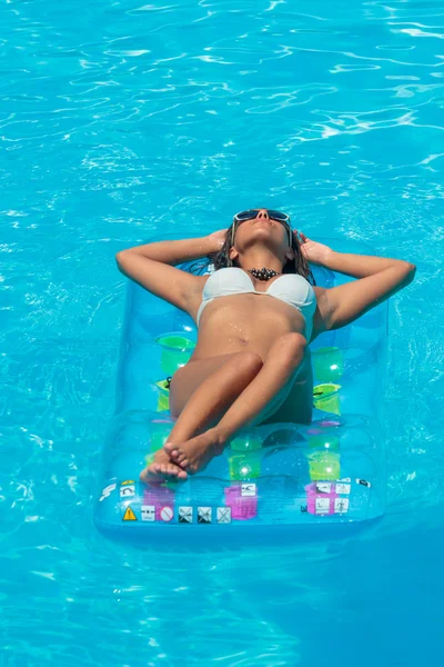 Uma menina está relaxando em uma piscina — Fotografia de Stock