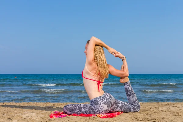 Kvinna utövar yoga på stranden — Stockfoto