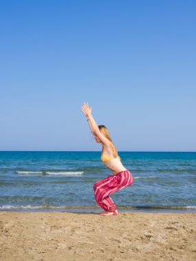 Kadın plajda yoga yapıyor.