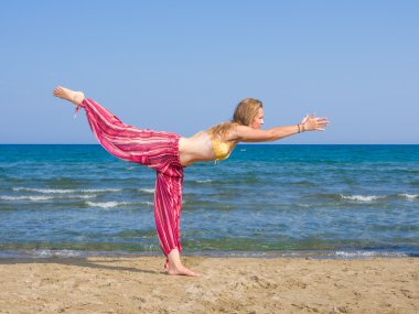 Kadın plajda yoga yapıyor.