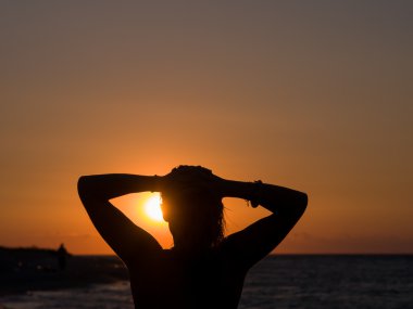 güzel gün batımı sırasında sahilde duran kadın.