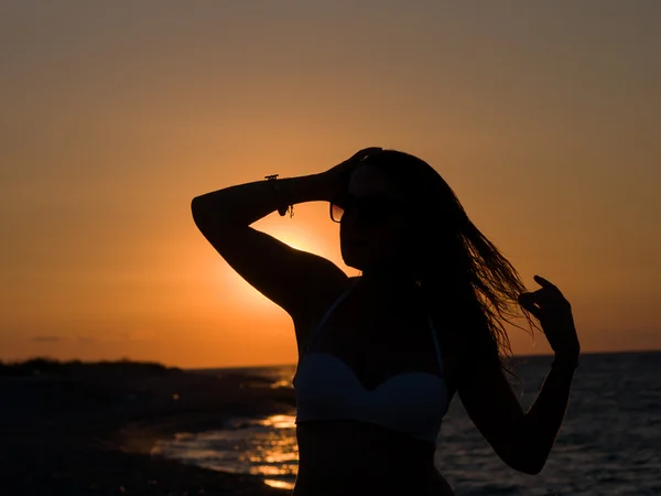 Kobieta stojąc na plaży podczas piękny zachód słońca. — Zdjęcie stockowe