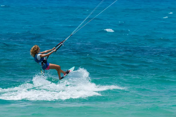 Μια νεαρή γυναίκα kite surfer βόλτες στη θάλασσα πρασινωπός-μπλε — Φωτογραφία Αρχείου